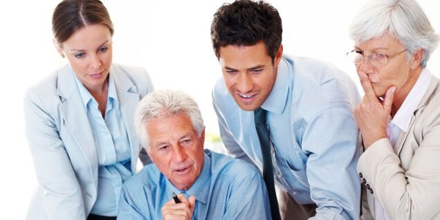 How To Convince Your Boss To Let You Attend Titanium Live? 1 Successful Mature Business Manager Working On Computer With His Colleagues At Desk